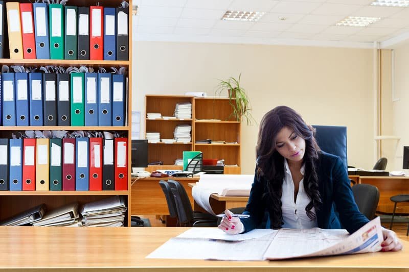 Woman reading a newspaper in an office